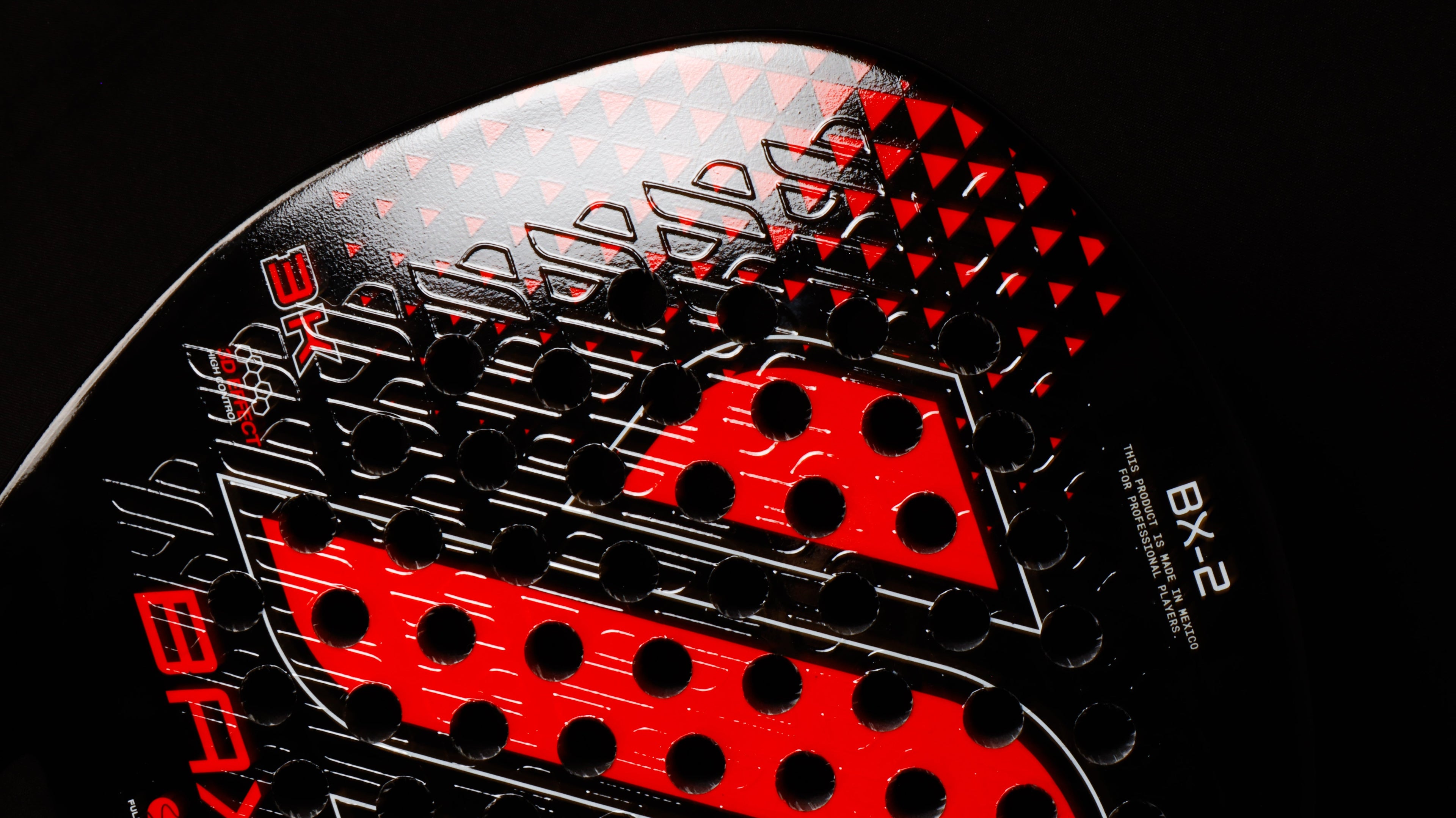 BX-2 apoyada en la reja con funda al lado, primer plano del relieve 3D en la cara.